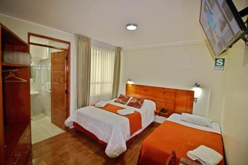 a hotel room with two beds and a bathroom at Munayki Hotel in Tacna