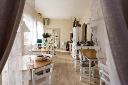 una cocina con mesas y sillas de madera y una cocina con electrodomésticos blancos. en 1920 Maison et Musique Hotel, en Cesenatico