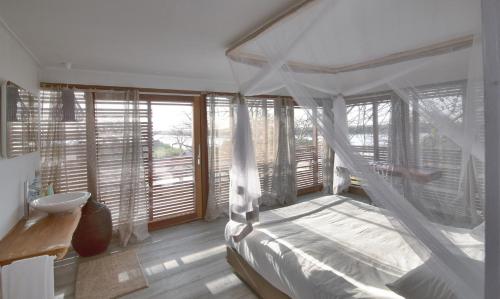 a bedroom with a bed with a canopy and windows at Les Palétuviers in Toubakouta