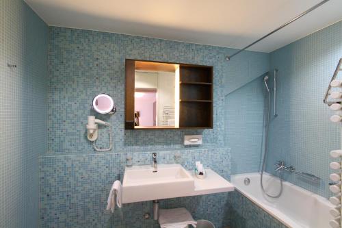 a bathroom with a sink and a mirror and a tub at Hotel Terminus Brugg in Brugg