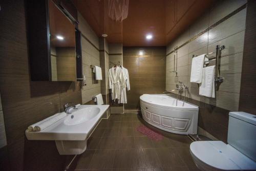 a bathroom with a tub and a toilet and a sink at Hotel Kremleff in Krasnodar