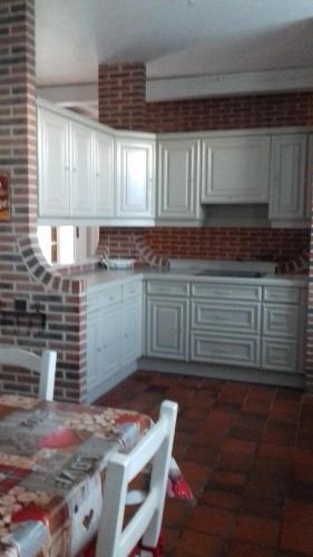 a kitchen with white cabinets and a table with chairs at Le gite des Menhirs in Mont-Saint-Éloi
