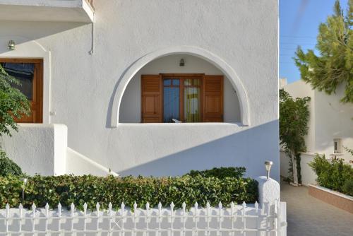 a white house with a white picket fence at Theoni Studios in Kastraki Naxou