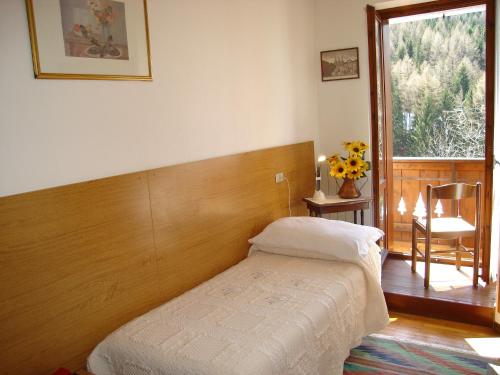 a bedroom with a bed and a chair and a window at Hotel Spampatti in Castione della Presolana