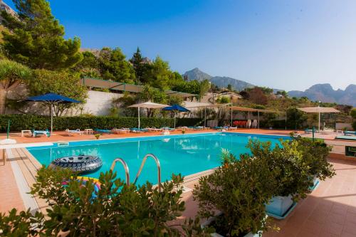 a large swimming pool with umbrellas and a resort at Hotel Pocho in San Vito lo Capo