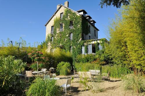 an old building covered in ivy with tables and chairs at Ty Mad in Douarnenez