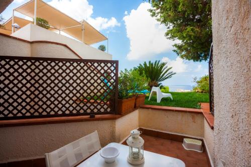 a table and chairs on a balcony with a view of a yard at Hotel Pocho in San Vito lo Capo