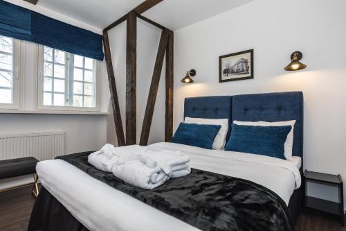 een slaapkamer met een groot bed met witte lakens en blauwe kussens bij Heritage House in Klaipėda