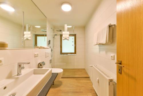 ein weißes Badezimmer mit Waschbecken und Spiegel in der Unterkunft Alpen Deluxe Oberammergau in Oberammergau