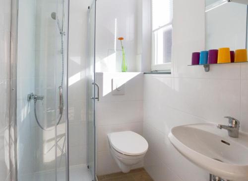 a white bathroom with a toilet and a sink at Apartment11 Wartburg in Cologne