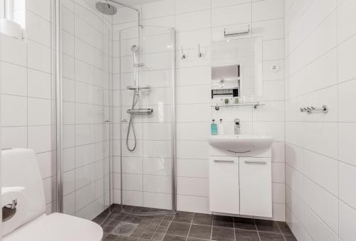 ein weißes Bad mit einer Dusche und einem Waschbecken in der Unterkunft Hällsnäs Hotell & Restaurang in Mölnlycke