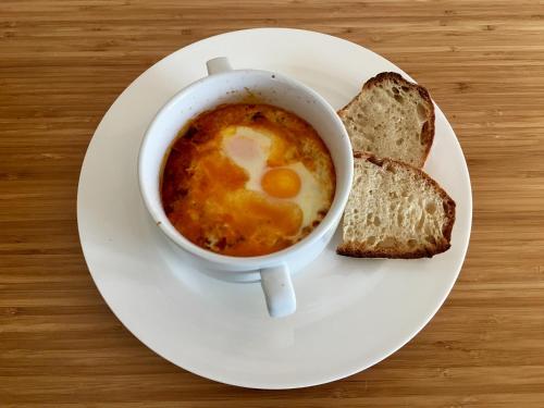 a white plate with a cup of soup and two slices of bread at Casa Donna Rosa B&B in Nuevo Arenal