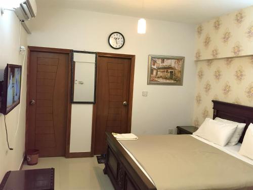 a bedroom with a bed and a clock on the wall at "Service Apartments Karachi" 3 Bed Javed Apartment in Karachi