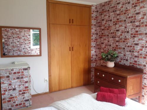 a bedroom with a brick wall and a bed and a dresser at Riversong in Ohakune
