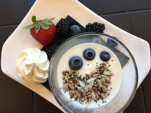 a plate with a bowl of yogurt with fruit and nuts at Wine Hotel San Giacomo Activity & Wellness in Paderno del Grappa