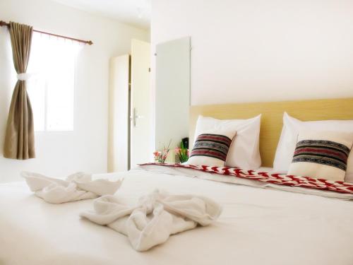 a white bed with white sheets and pillows at LEOS Hotel in Tomohon