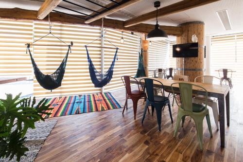 a dining room with a table and chairs and hammocks at 365BASE outdoor hostel in Hamamatsu