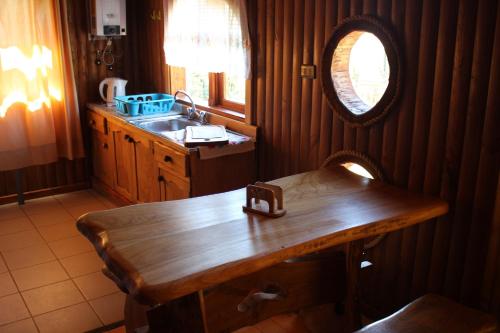 a kitchen with a wooden table and a sink at Cabañas Mis Viejos in Panguipulli