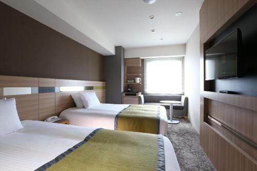 仙台市にあるアルモントホテル仙台のベッド2台、薄型テレビが備わるホテルルームです。