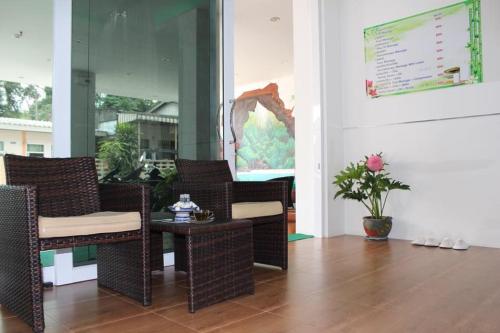 a room with wicker chairs and a table on a porch at Namthip Residence in Trang