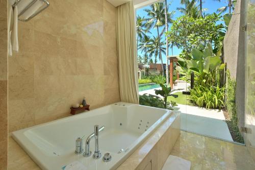 Una bañera en un baño con una ventana grande. en Candi Beach Resort & Spa, en Candidasa