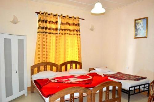 a bedroom with two beds and a yellow curtain at Highcliffe Guest House in Haputale