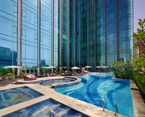 a pool in a building with chairs and umbrellas at The Reverie Saigon in Ho Chi Minh City