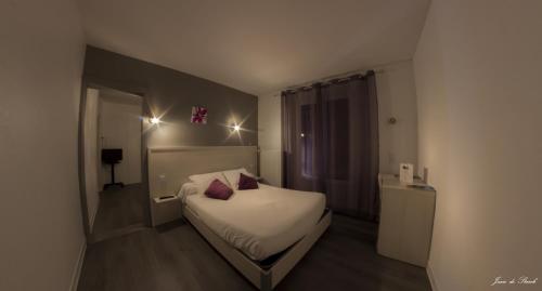 a bedroom with a bed with two red pillows on it at Logis Hôtel Le pont d'Arcole in Riscle