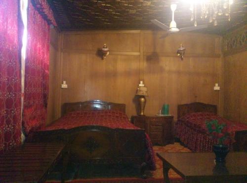 a bedroom with two beds and a table in it at Chicago Group of Houseboats in Srinagar