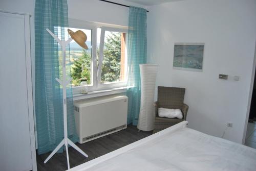 ein Schlafzimmer mit einem Bett, einem Fenster und einem Stuhl in der Unterkunft Talblick Gleiberg in Krofdorf-Gleiberg