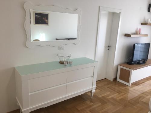 - une commode avec un miroir et une télévision dans l'établissement Apartment Posejdon, à Belgrade
