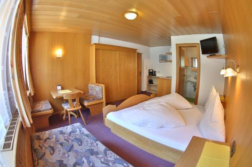ein kleines Schlafzimmer mit einem Bett, einem Tisch und einem Schreibtisch in der Unterkunft Ferienhof Riml in Sölden