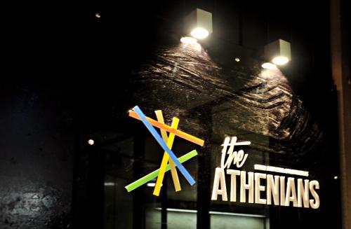 a store window with a sign with colored pencils on it at The Athenians Modern Apartments in Athens