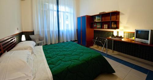 a bedroom with a bed with a green blanket at Hotel Villa Sturzo in Caltagirone