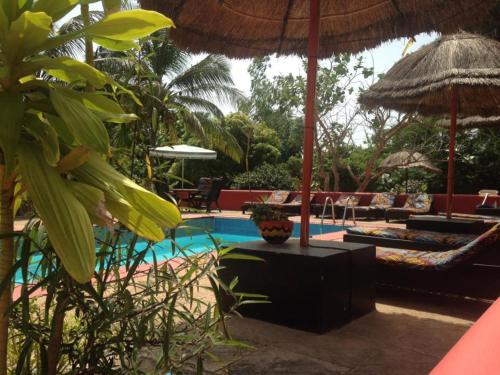 a resort with a pool with chairs and an umbrella at The Gunjur Project Lodge in Gunjur