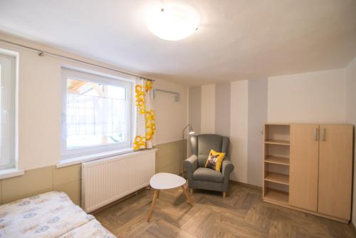 a bedroom with a bed and a chair and a window at Apartmány Lea in Liptovský Mikuláš