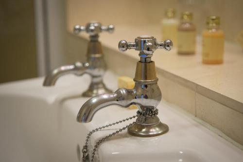 a bathroom sink with two faucets on it at Lake Vyrnwy Hotel & Spa in Llanwddyn