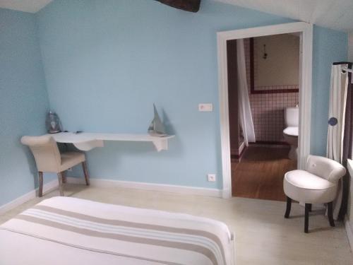 a bedroom with a blue wall with a bed and a chair at Le Marais Picotin in Saint-Pierre-le-Vieux
