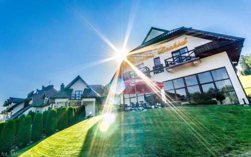 a house with the sun shining in front of it at Hotel Kompleks Beskid z basenem i stokiem narciarskim - blisko Babiej Góry in Spytkowice