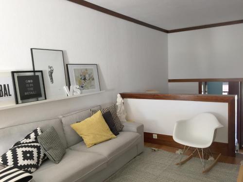 uma sala de estar com um sofá e uma cadeira em casa das conchas em Tróia