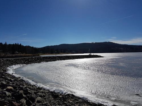 a large body of water with snow on the shore at Chalupa na Lipně - Holiday House 1 in Lipno nad Vltavou