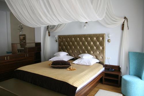 a bedroom with a bed with a headboard and a blue chair at Hotel Kilometrul Zero in Drăgăşani