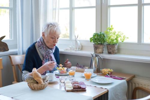 an older woman sitting at a table eating food at Hotel Spiekeroog in Spiekeroog