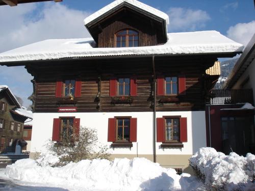 a wooden house with red shutters in the snow at Landhaus Torghele in Schruns