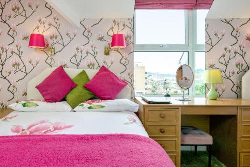 a bedroom with pink and green pillows and a desk at Marine Hotel in Paignton