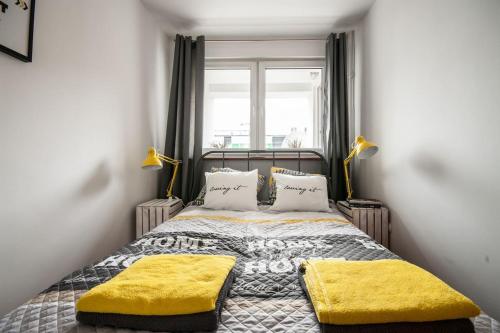 - une chambre avec un lit doté d'oreillers jaunes et d'une fenêtre dans l'établissement Apartament ul.Złota z widokiem na Pałac Kultury!!!, à Varsovie