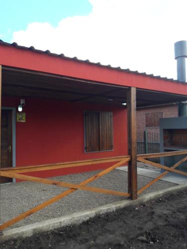 a red building with a fence in front of it at Carmelo RIVERSIDE Bungalows in Carmelo
