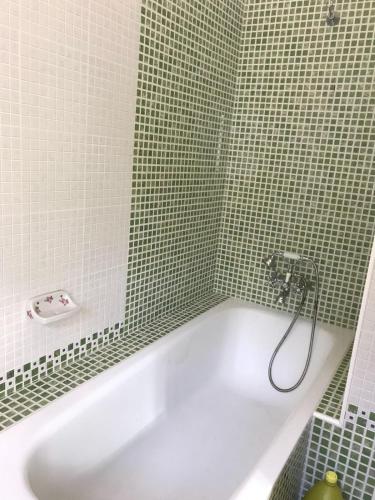 a white bath tub in a green tiled bathroom at Casa rural en Constantina in Constantina
