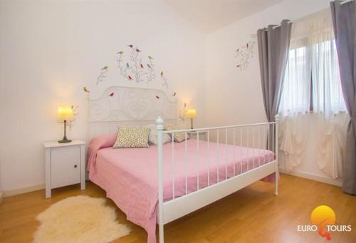 a pink and white bed in a white room at Holiday Home Marina in Kaštelir