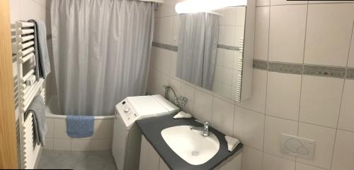 Baño blanco con lavabo y espejo en Apartment Center Zermatt, en Zermatt